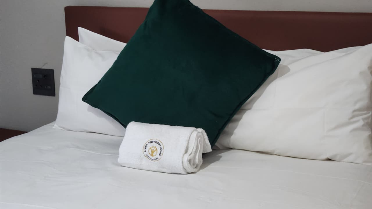 Detail - branded towel on deep green cushion, crisp white pillows